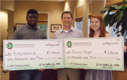 Dr. Spillers holding two giant checks with scholarship winners, Rickey and Ellie