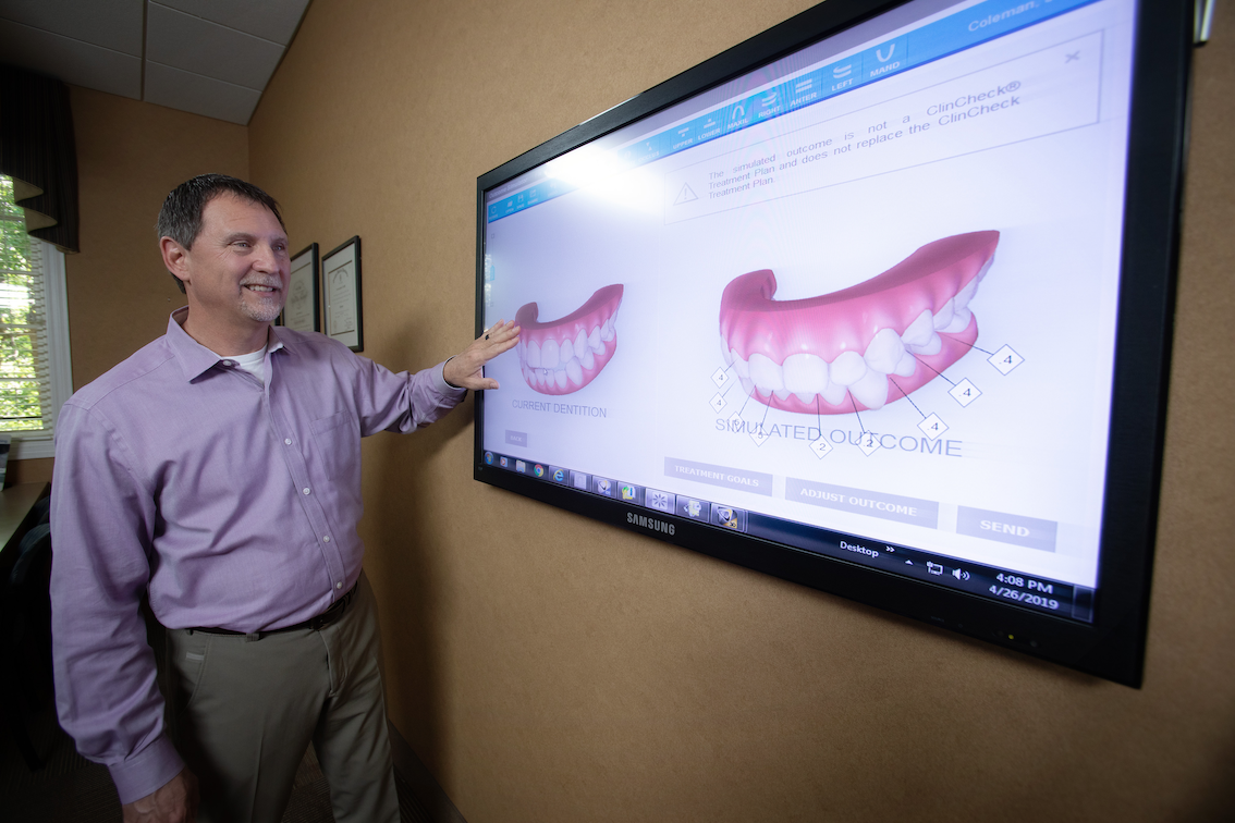 Dr. Spillers, Spillers Orthodontics, pointing at dental diagram on screen, teaching, smiling