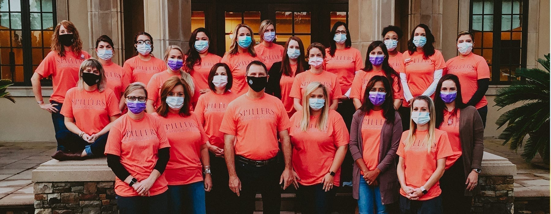 Group of people standing on steps, wearing mask, wearing red shirts, Spillers Orthodontics