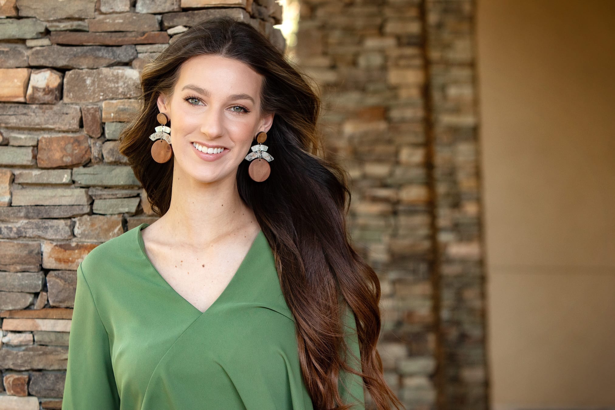 Woman standing in front of Spillers Orthodontics, wearing green shirt with long brown hair